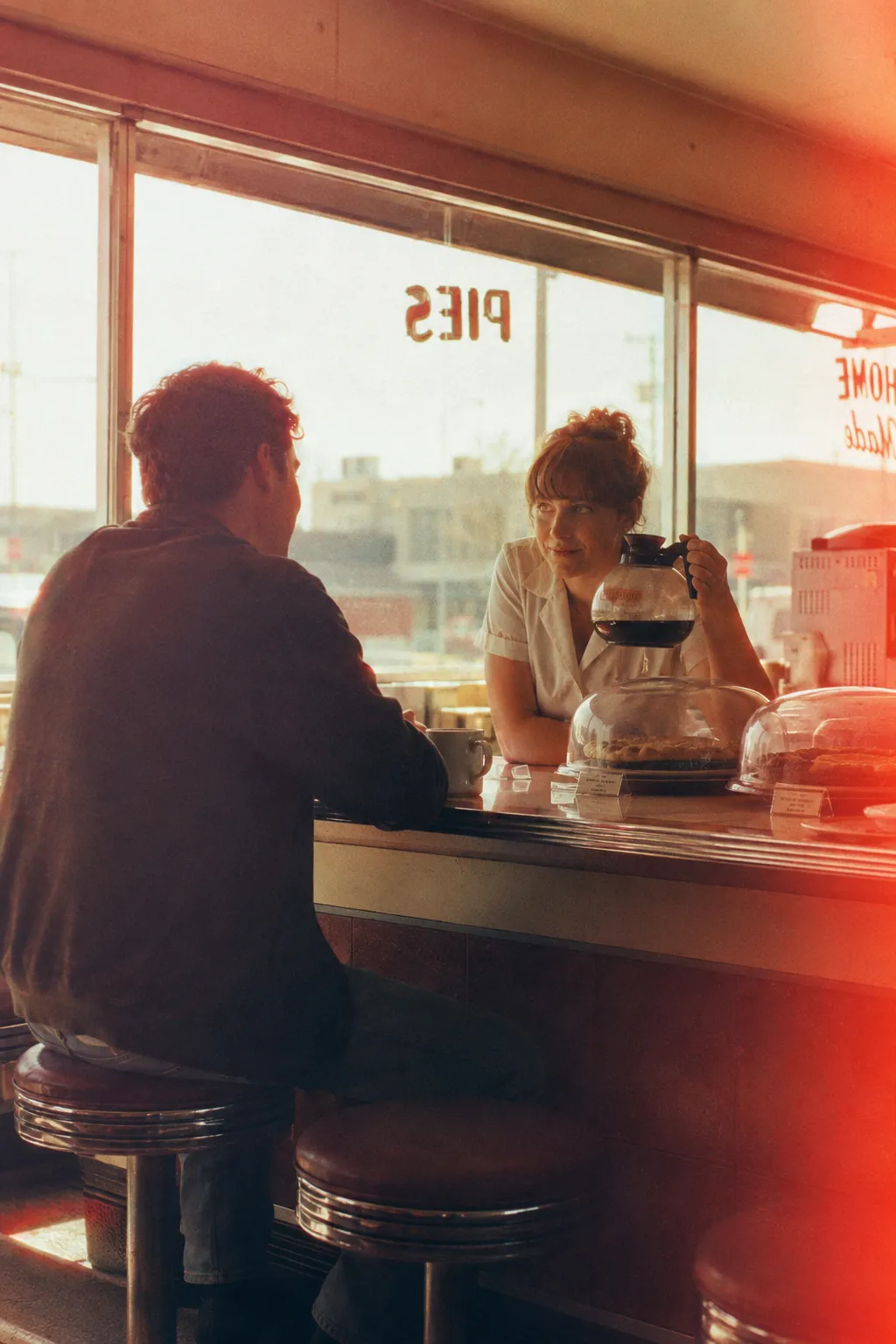 The window behind the counter blooms outward and edges both figures in a warm halo.