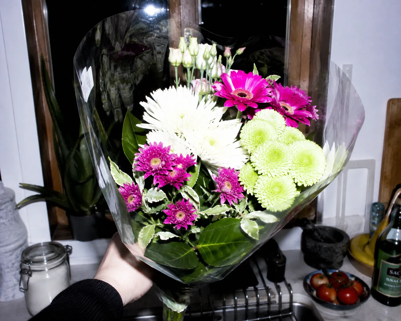 The nearest petals blow out flat while the window behind reads almost black.